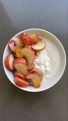 peaches and yogurt in a white bowl on a gray countertop, ready to be eaten