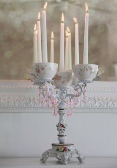 there are many candles that are lit in the candle holder on the table with dishes