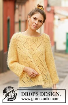 a woman standing in the street wearing a yellow sweater