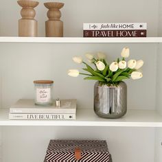 some white flowers are in a vase on top of two books and a small box