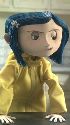 a doll with blue hair sitting on top of a table in front of a counter