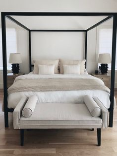 a four poster bed with white linens and pillows