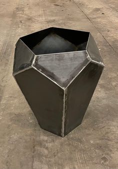 a black vase sitting on top of a cement floor