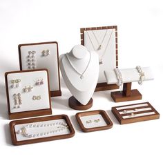 an assortment of jewelry displayed on wooden stand with white necklaces, bracelets and earrings