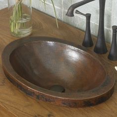 a bathroom sink sitting on top of a wooden counter next to a vase filled with flowers