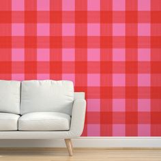 a white couch sitting in front of a red and pink checkered wallpapered background