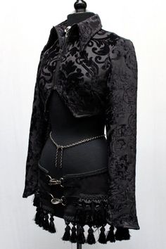 A jacket with a hauntingly dark style! A stylish women's crop jacket made in luxurious black velvet fabric with an ornate swirling design on it. The jacket has a high pointed collar and zips in front with a blackened gunmetal zipper. The sleeves are tapered and have a pointy bell shaped cuff. In back the jacket has a fancy duck tail that is split in the middle. So much style! Comes in sizes Small-XXL. Sizes: Small - Chest 34" Shoulders ( shoulder seam to shoulder seam across upper back) 14.5" Me Black Velvet Costume Outerwear, Gothic Fitted Velvet Outerwear, Black Gothic Velvet Outerwear, Fitted Gothic Velvet Outerwear, Black Velvet Gothic Outerwear, Gothic Long Sleeve Velvet Outerwear, Womens Cropped Jacket, Black Velvet Fabric, Printed Velvet