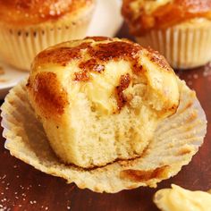 two muffins sitting on top of a wooden table next to each other with one bite taken out