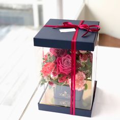 a blue box with pink and red flowers in it sitting on a white table top