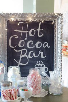 hot cocoa bar sign with candy and candies on the table in front of it