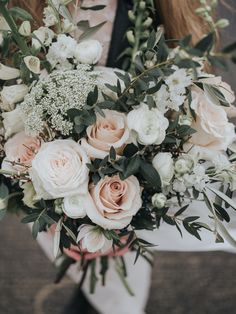 a bouquet of white and pink flowers in a vase with greenery on the side