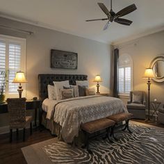 a bedroom with a zebra print rug on the floor and a bed in front of two windows