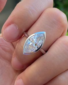 a woman's hand holding an engagement ring with a pear shaped diamond in it