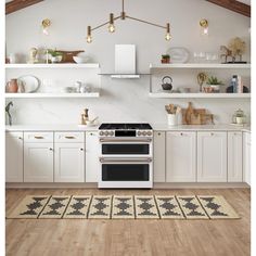 an open kitchen with white cabinets and black stove top oven in the center, surrounded by wooden flooring