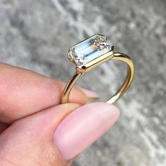 a person is holding a ring with an aquamarine colored stone in it's center