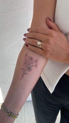 a woman's arm with a small flower tattoo on the left side of her arm