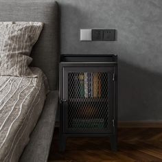 a nightstand with books and magazines on it next to a bed in a gray bedroom