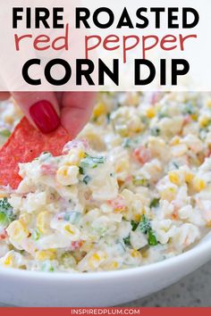 a hand dipping a cracker into a bowl of fire roasted red pepper corn dip