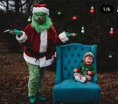 a small child sitting on a blue chair next to an adult dressed as the grinch