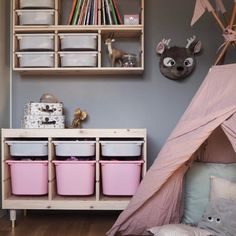 a child's playroom with pink storage bins