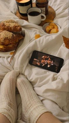 a person laying in bed with food and drinks