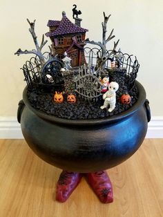 a black pot filled with halloween decorations on top of a wooden floor