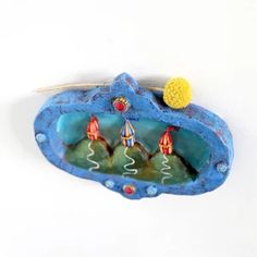 a blue and yellow object with two small boats on it's side, sitting on a white surface