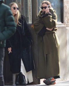 two women standing on the sidewalk talking on their cell phones