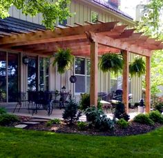 an outdoor patio with wooden pergols and plants on the ground in front of a house