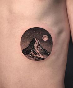 a man's chest with a mountain and moon tattoo on the left side of his stomach