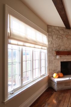 an empty living room with wood floors and stone fireplace in the center, surrounded by large windows