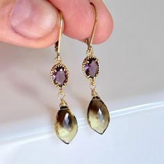 Amethyst and Bi Color Quartz Earrings, Purple and Brown Statement Earrings in Gold or Silver, Colorful Jewelry, Holiday Gift idea for her These rich and colorful earrings feature 6 mm faceted Amethyst oval stones prong set in 14k Gold filled or sterling silver. Suspended from the purple ovals are 12 mm natural Bicolor Quartz faceted teardrops wire wrapped in the finish of your choice. The earrings come in lever back ear wires. These are perfect vivid and colorful earrings with a unique color com February Stone, Contemporary Jewelry Earrings, Copper Dress, Purple And Brown, Silver Gift Wrap, Color Quartz, Unique Color Combinations, Family Jewels, Earrings Purple