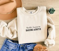 Introducing the "World's Sweetest Baking Auntie" sweatshirt, perfect for the aunt who bakes with love! This cozy and stylish sweatshirt celebrates both family and baking, making it an ideal gift for any baking-loving aunt. Whether she's whipping up sweet treats or spending time with loved ones, this sweatshirt is the perfect way to show her appreciation. Great for birthdays, holidays, or just because! Personalization: * Text colors are available in brown, black, white, and white glitter.  * Whit Auntie Sweatshirt, Aunt Sweatshirt, Baking Gift, Glitter Text, Auntie Gifts, Baking Gifts, Aunt Gifts, White Glitter, Text Color