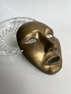 a gold mask sitting on top of a glass plate