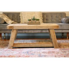 a wooden coffee table sitting on top of a rug in front of a gray couch