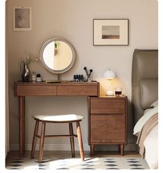 a desk with a mirror, stool and pictures on the wall above it in a bedroom