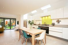 an open kitchen and dining room area with white cabinets, wood table and green chairs