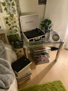 a bed room with a table and a record player on top of it next to a pile of books