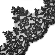 black lace with flowers and leaves is shown on a white background in close up view