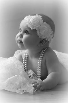 a baby wearing pearls and a flower in her hair