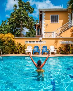 a person in a swimming pool with their arms raised above the water and chairs around them