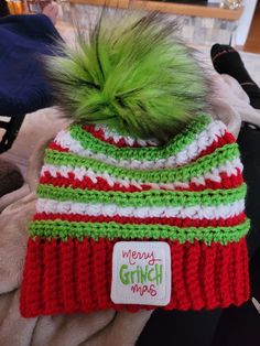 a green and red knitted hat with a fuzzy pom