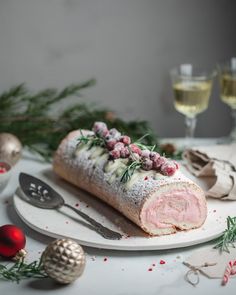 a white plate topped with a roll covered in frosting and cranberry toppings