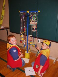 two young boys sitting on the floor in front of a machine with wires attached to it