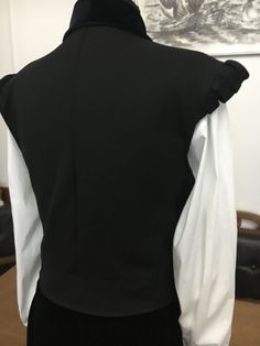 the back of a woman's black and white jacket on display in front of a painting