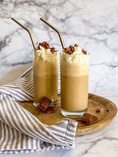 two glasses filled with ice cream sitting on top of a wooden tray