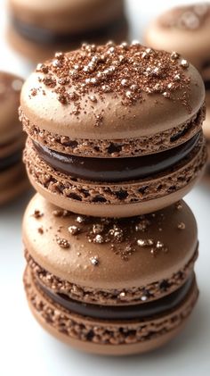 a stack of cookies with chocolate frosting and sprinkles on top, sitting next to each other