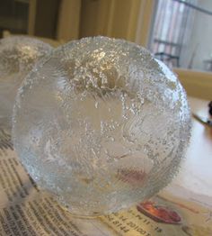 two clear glass vases sitting on top of a newspaper