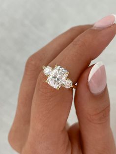 a woman's hand holding an engagement ring with three stones