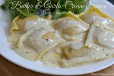 a white plate topped with ravioli covered in gravy next to a salad